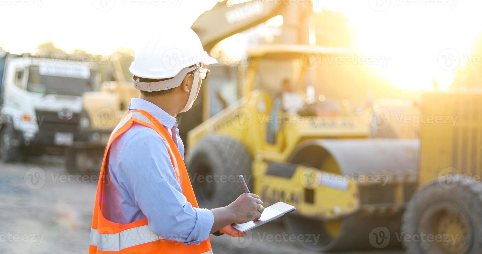 Aziatische ingenieur met veiligheidshelm met behulp van tablet pc-computer inspecteren en werken op de bouwplaats foto