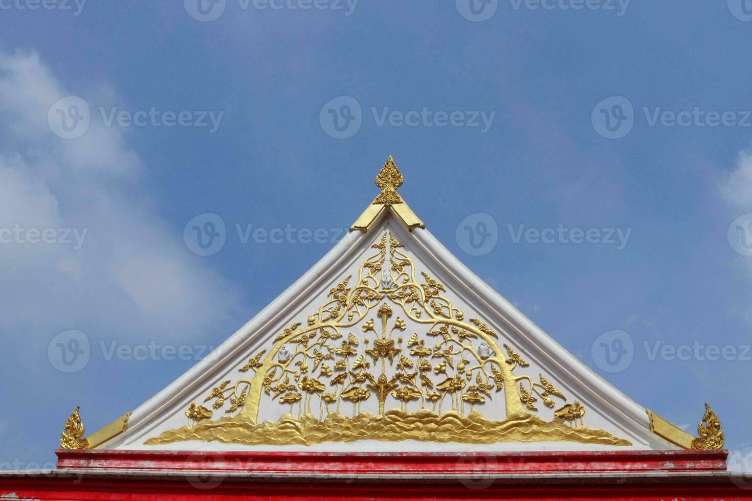 oude inheems wit cement gelijkbenig driehoek vorm geveltop en goud Thais inheems kunst van Boeddhisme kerk en licht blauw lucht met wolk achtergrond, Thailand. foto