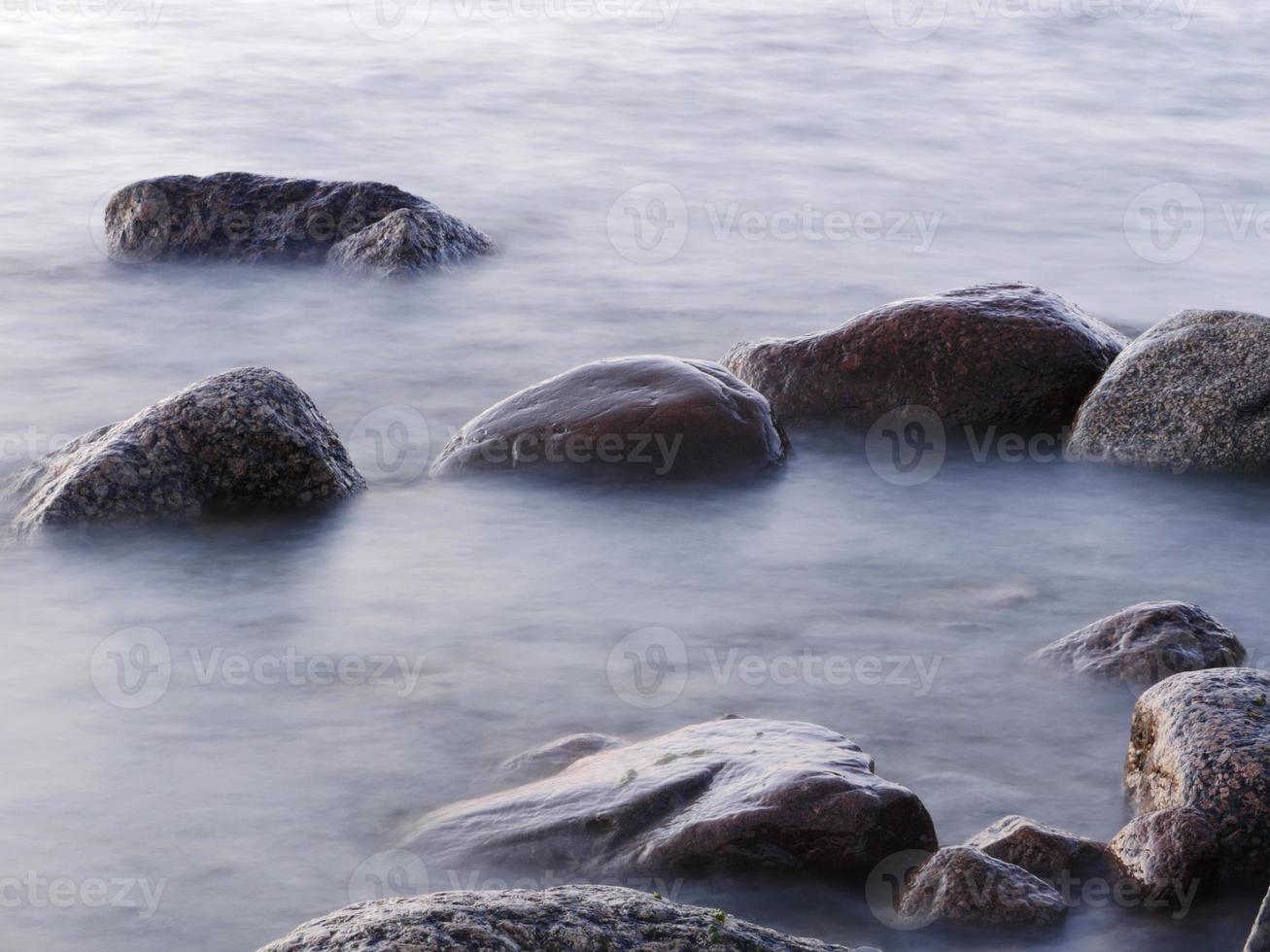 grote gladde rotsblokken aan de kust in de mist lange blootstelling foto