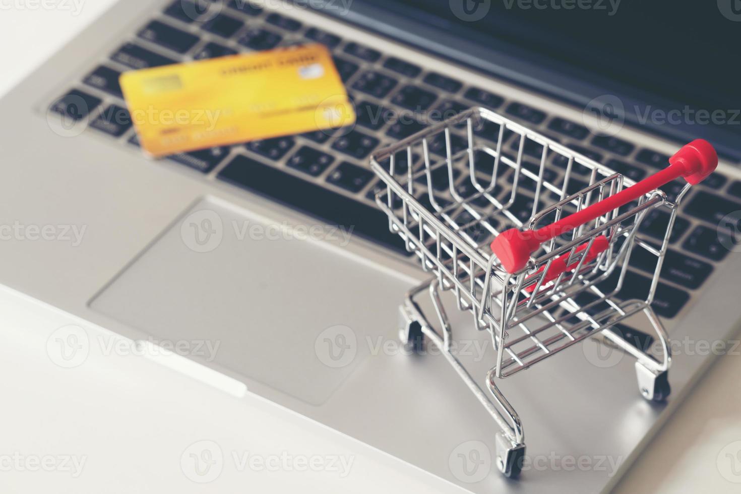 winkelwagentje en creditcard met laptop op het bureau foto