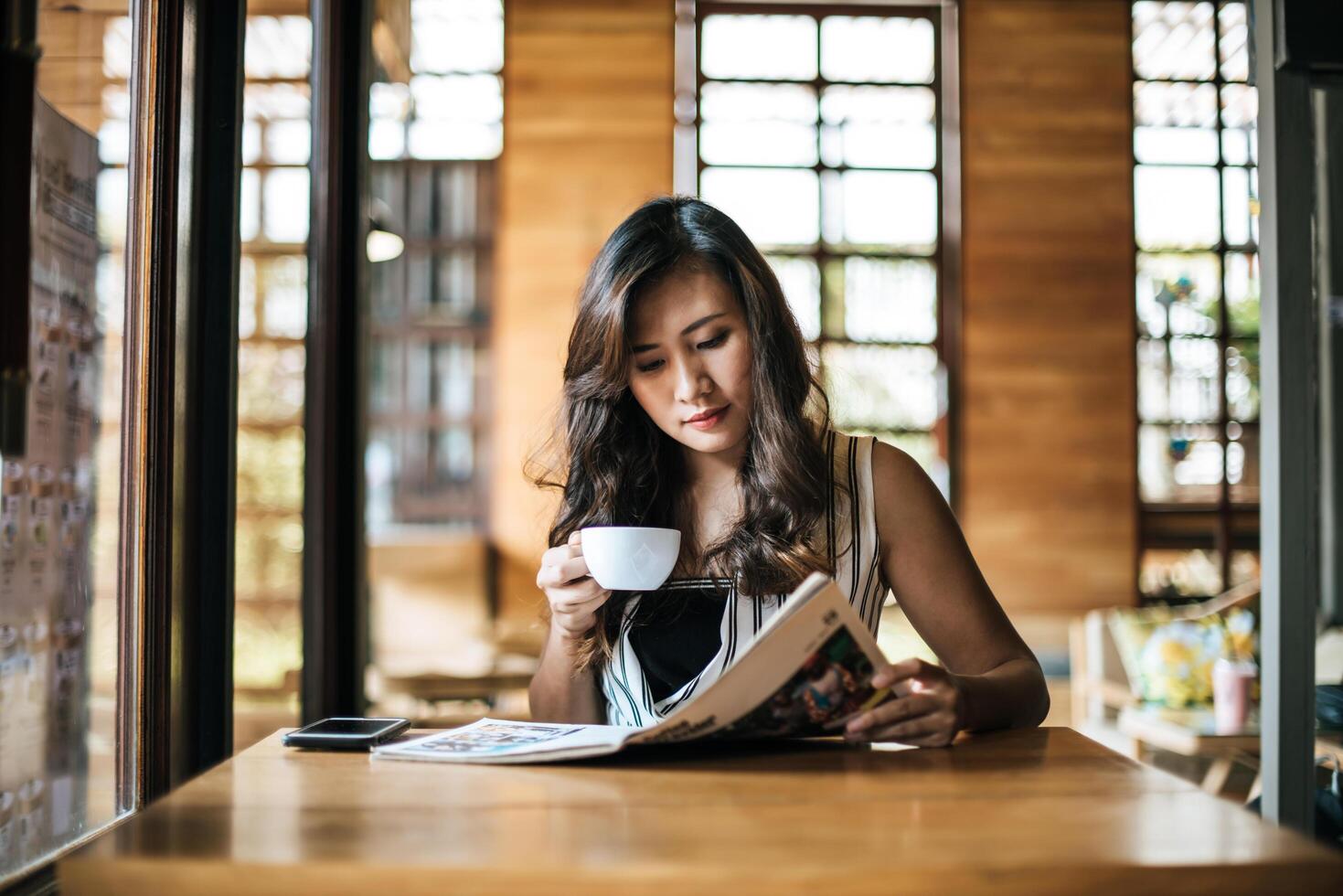 mooie vrouw die tijdschrift leest in café foto