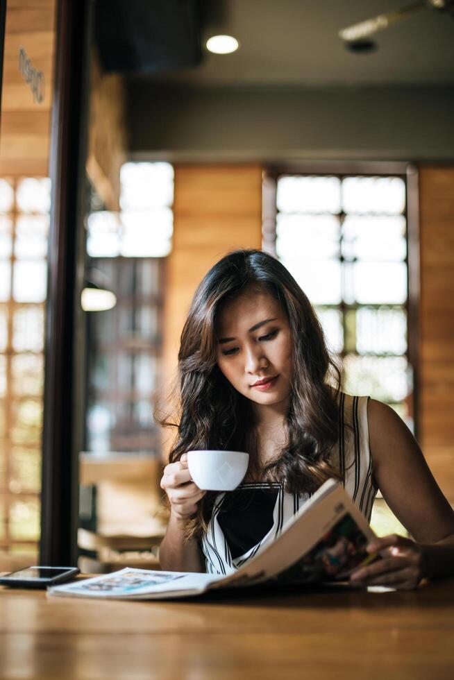 mooie vrouw die tijdschrift leest in café foto