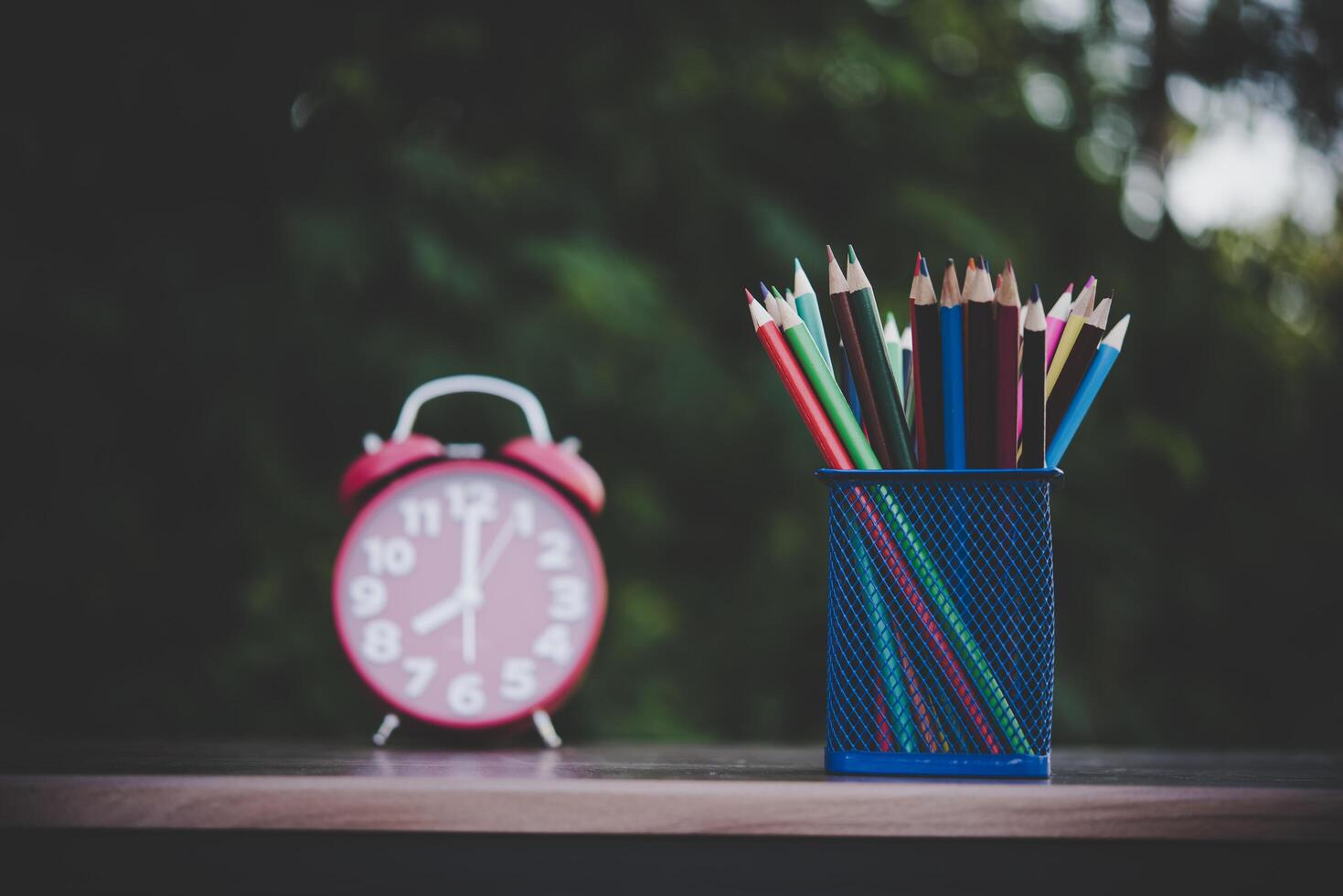 wekker en kleurpotloden op de houten tafel met bokeh foto