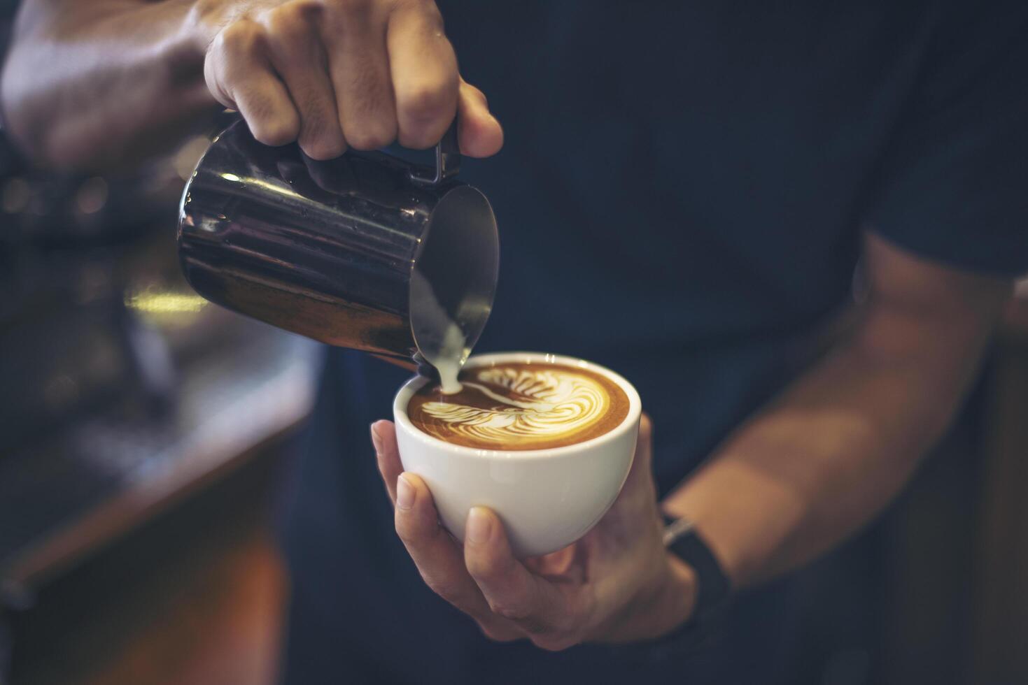close-up van handen barista maakt latte koffie kunst verf foto