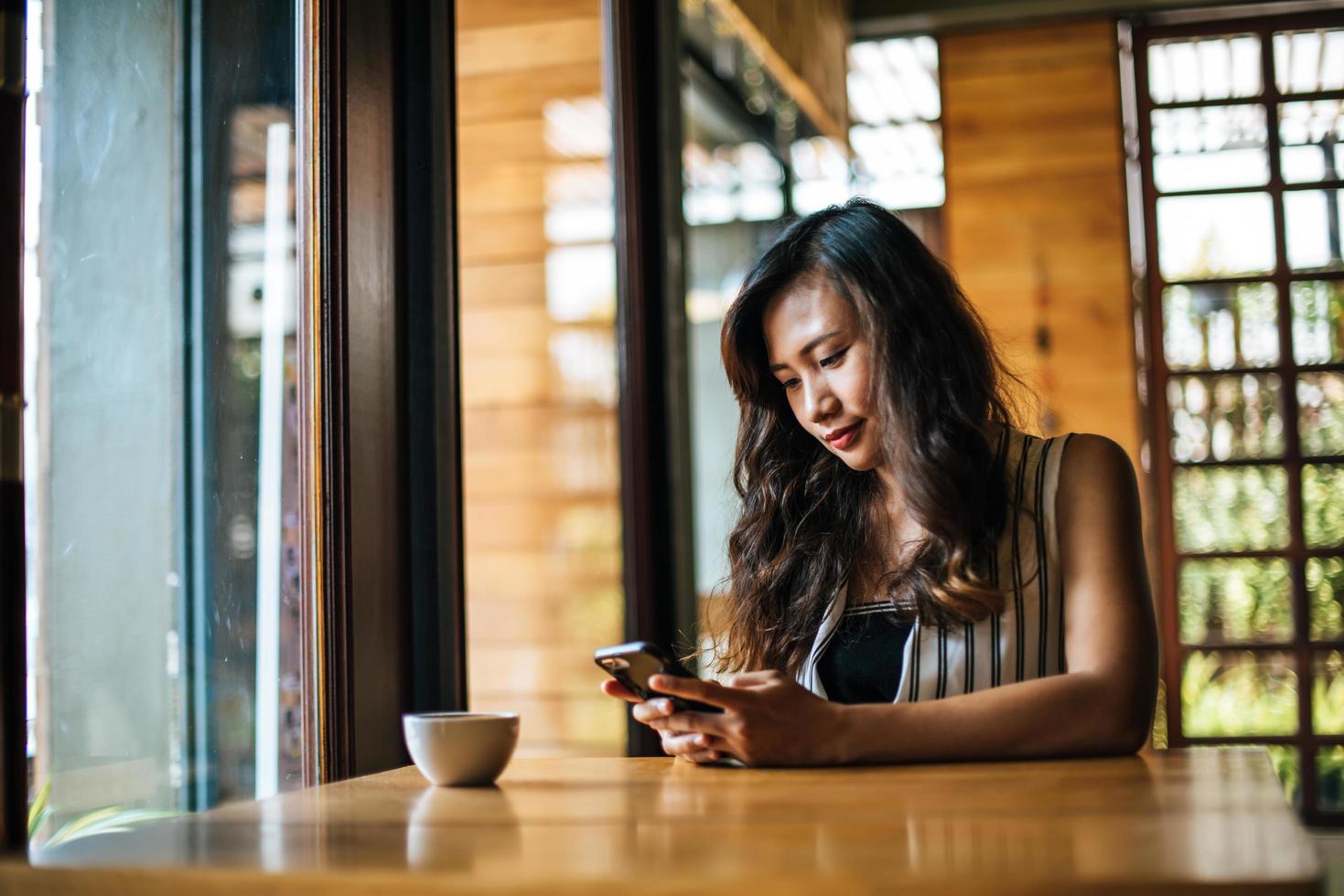 vrouw zit en speelt haar smartphone in café foto