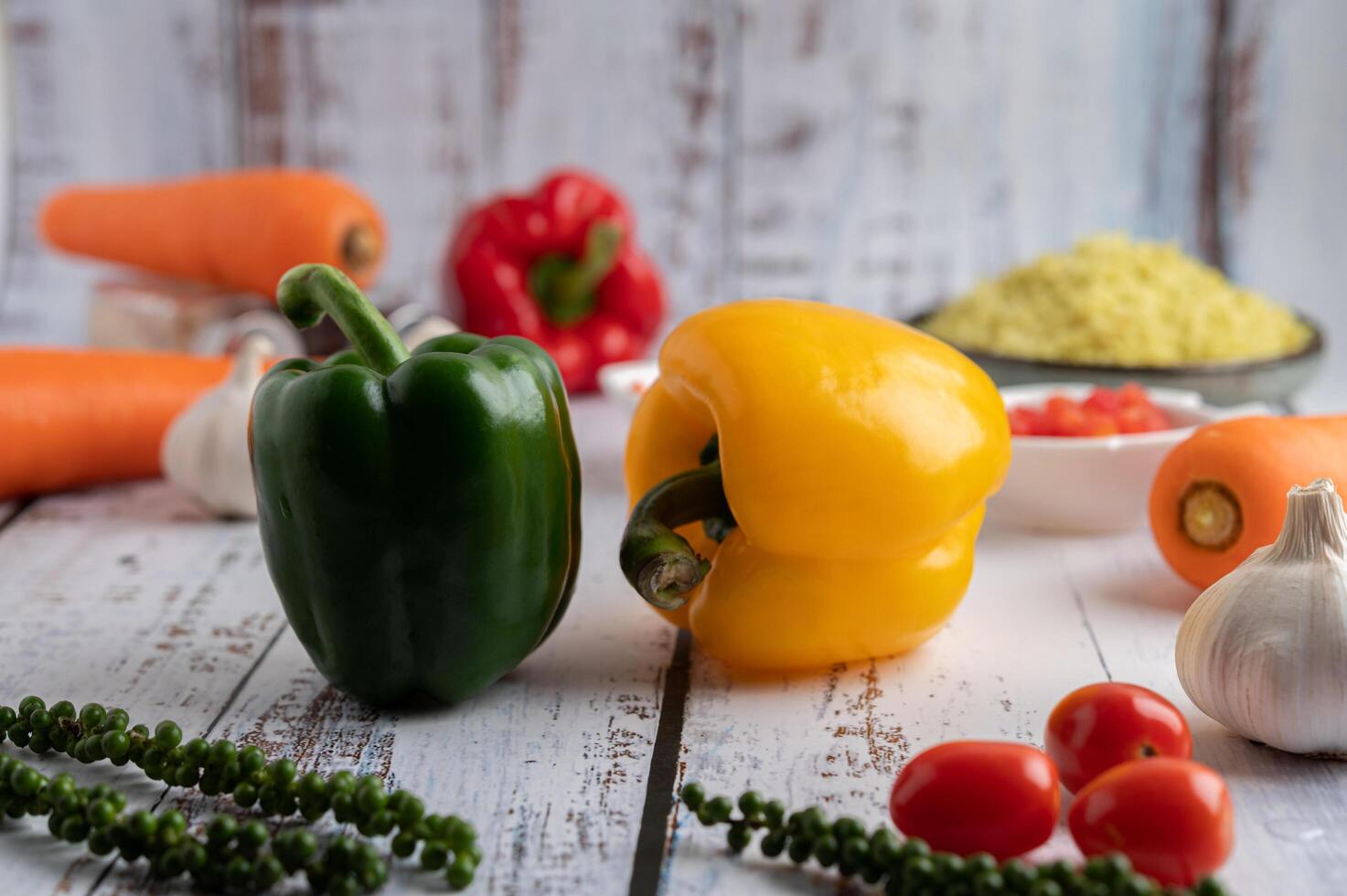 paprika, verse paprika, tomaten, knoflook en wortelen op een witte houten achtergrond. foto
