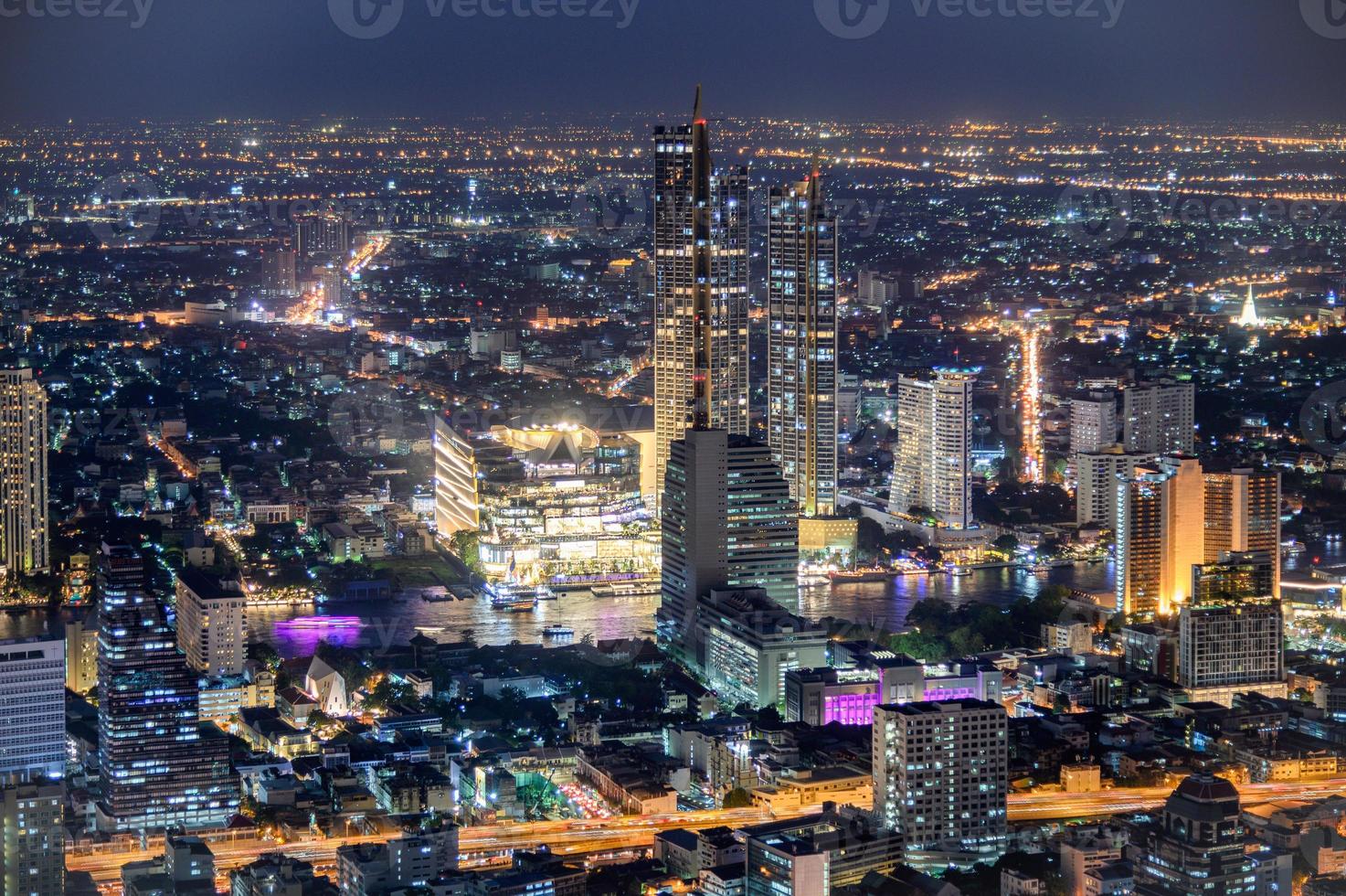 stadsgezicht van verlicht gebouw met warenhuis in de buurt van de chao phraya-rivier foto