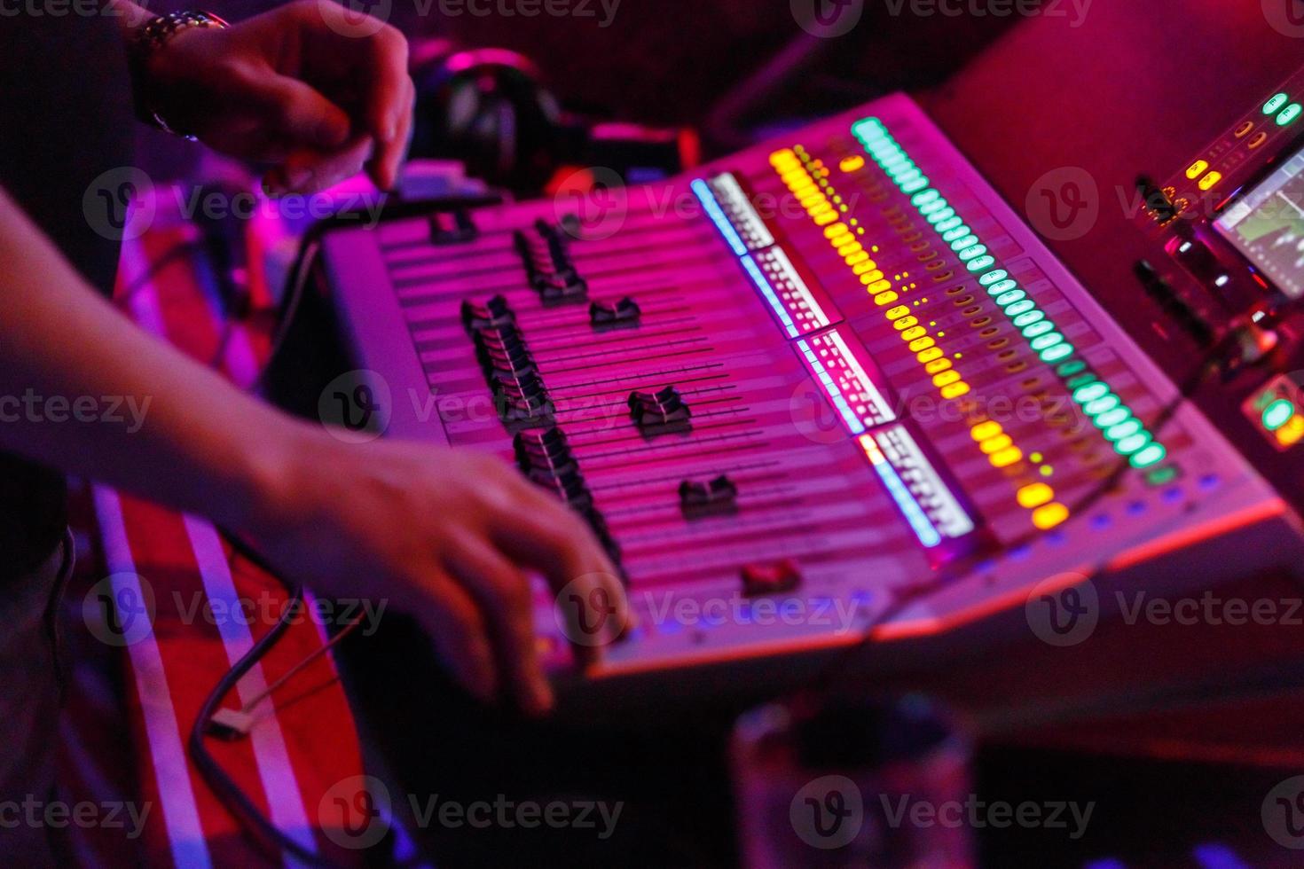 geluidstechnicus die werkt met concertgeluidsapparatuur - audiomixing muziekconsole met verlichte knoppen. foto