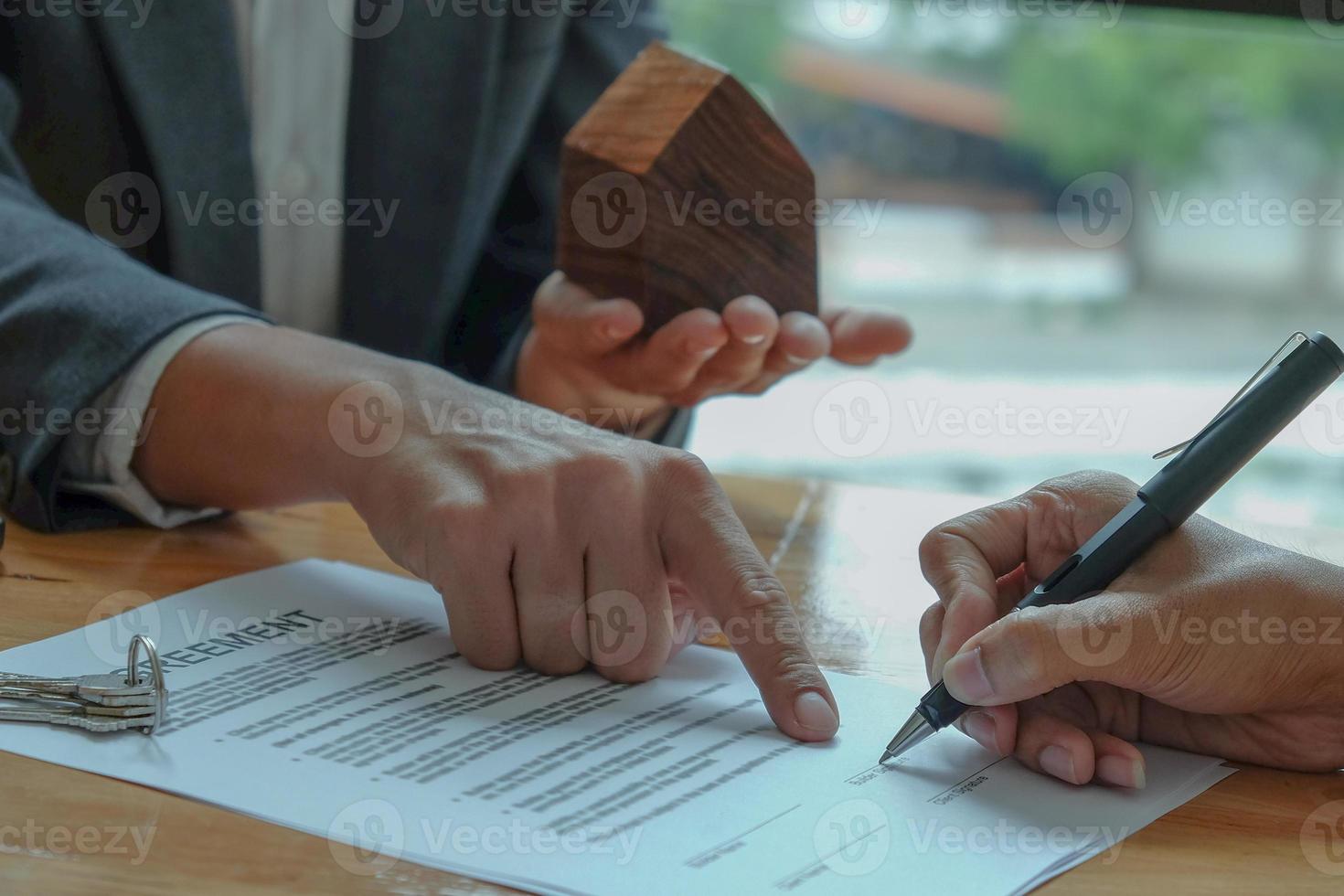 zakenlieden die het huis verkopen wijzend op de ondertekening van het verkoopcontract op kantoor. foto