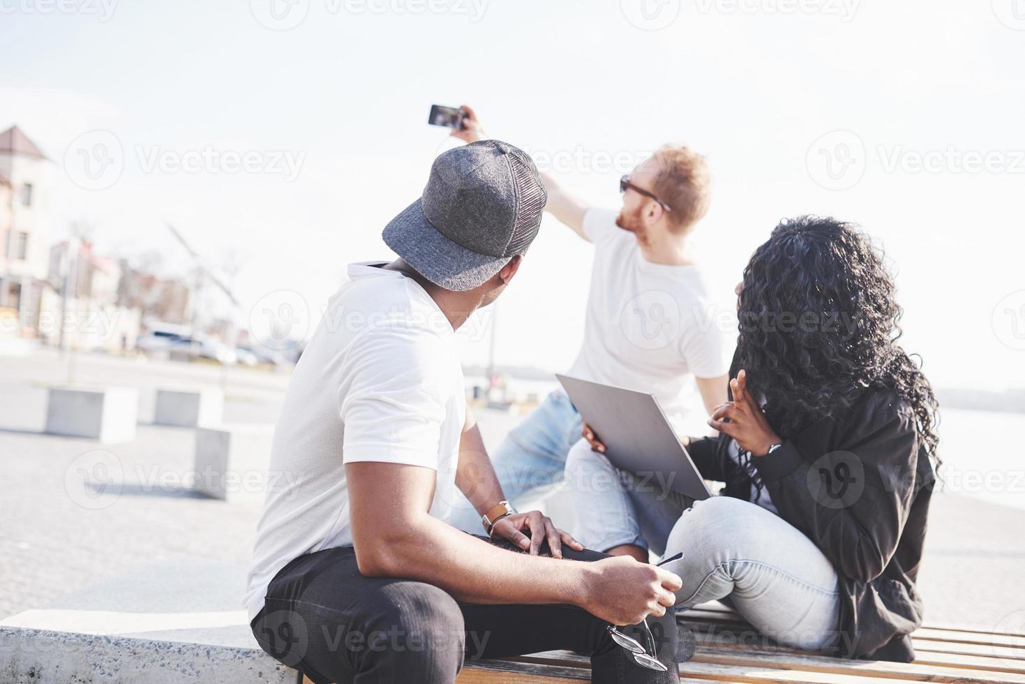 mooie multi-etnische vrienden die een laptop op straat gebruiken en selphie maken. jeugd levensstijl concept foto