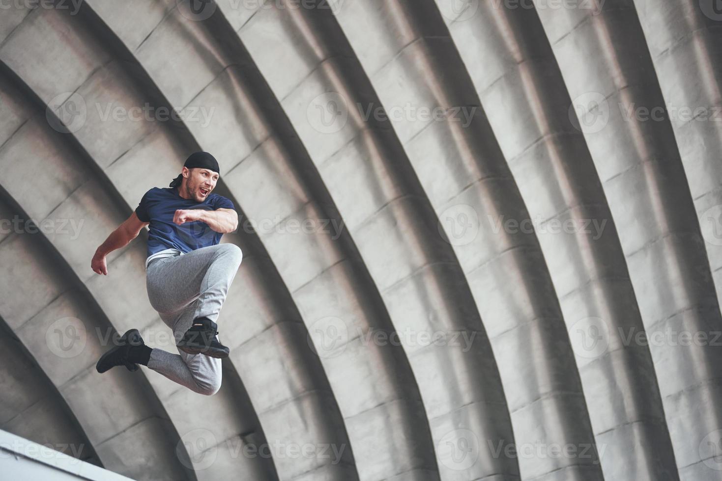 jonge man doet parkour sprong in stedelijke ruimte in de stad zonnige lente zomerdag. foto