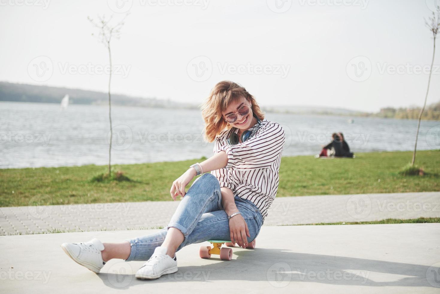 een mooi jong meisje heeft plezier in het park en rijdt op een skateboard foto