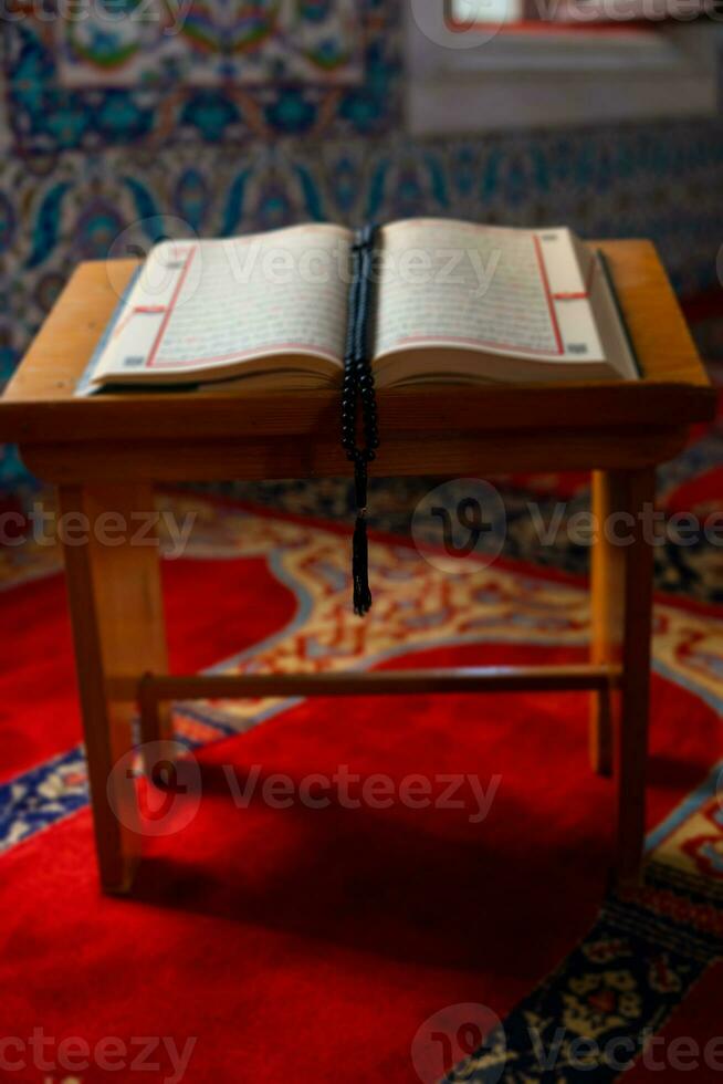 de heilig koran Aan de lessenaar met een rozenkrans of bidden kralen in de moskee foto