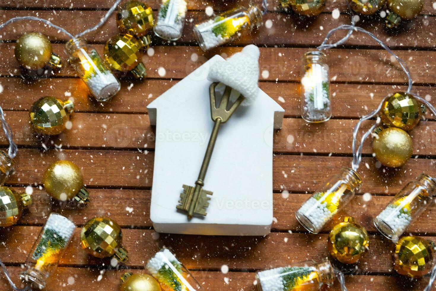 sleutel naar huis met een sleutelhanger klein huis Aan houten achtergrond met Kerstmis decor indeling. geschenk voor nieuw jaar, kerstmis. gebouw, projecteren, in beweging naar nieuw huis, hypotheek, huur en aankoop echt landgoed foto