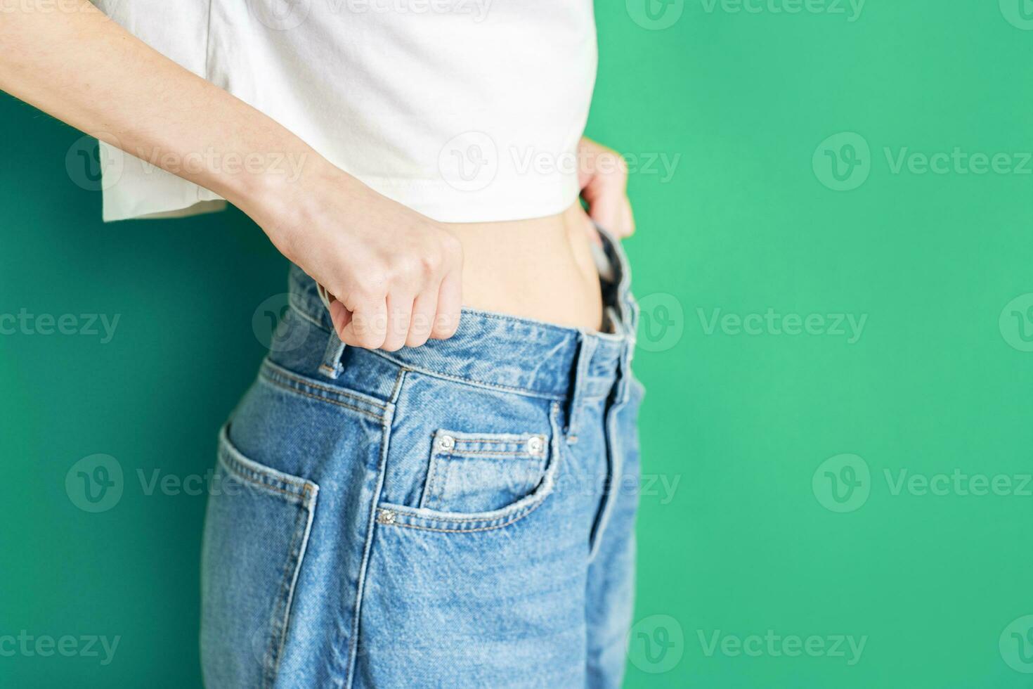 de meisje is Holding jeans dat zijn te groot. foto