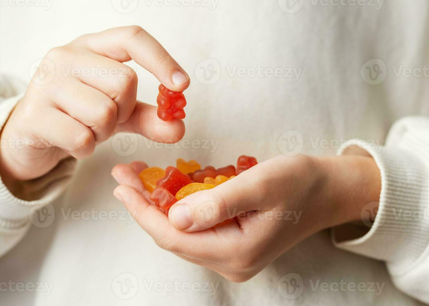 een meisje houdt een kleverig beer vitamines in haar handen foto