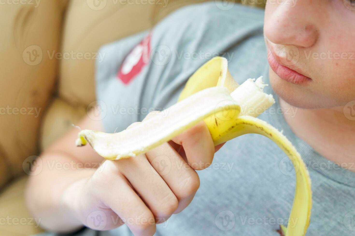 portret van een tiener- jongen aan het eten een banaan. foto van een jongens mond en lippen met een banaan. vers fruit. gezond voedingsmiddelen voor kinderen