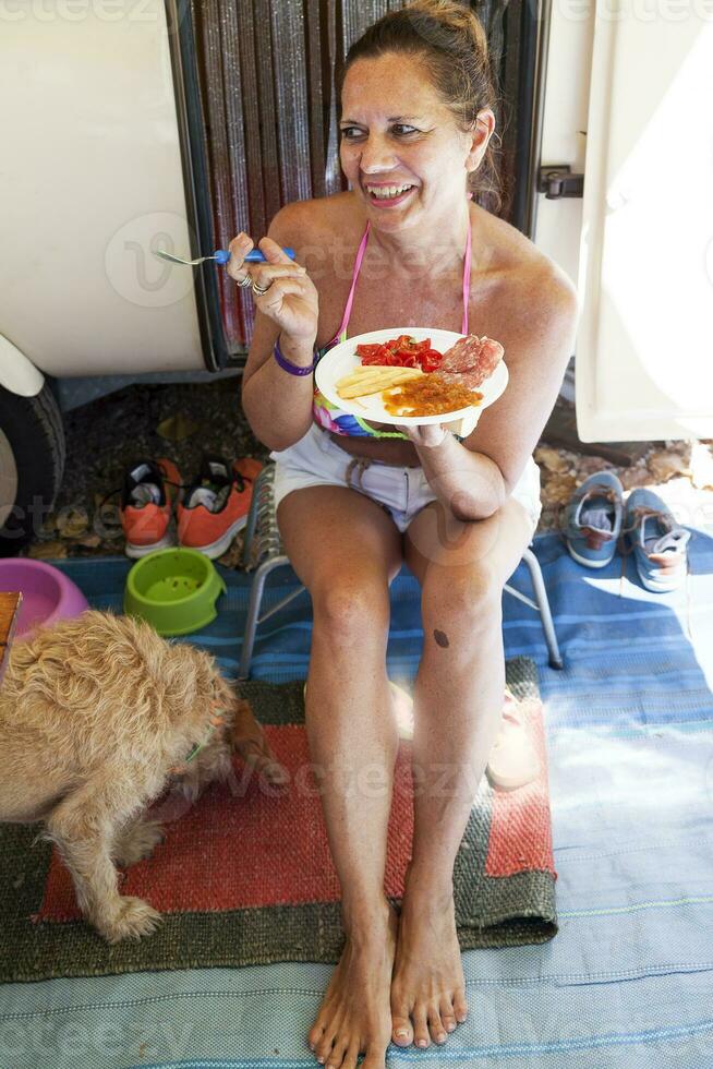 mooi vrouw zittend in voorkant van caravan aan het eten foto