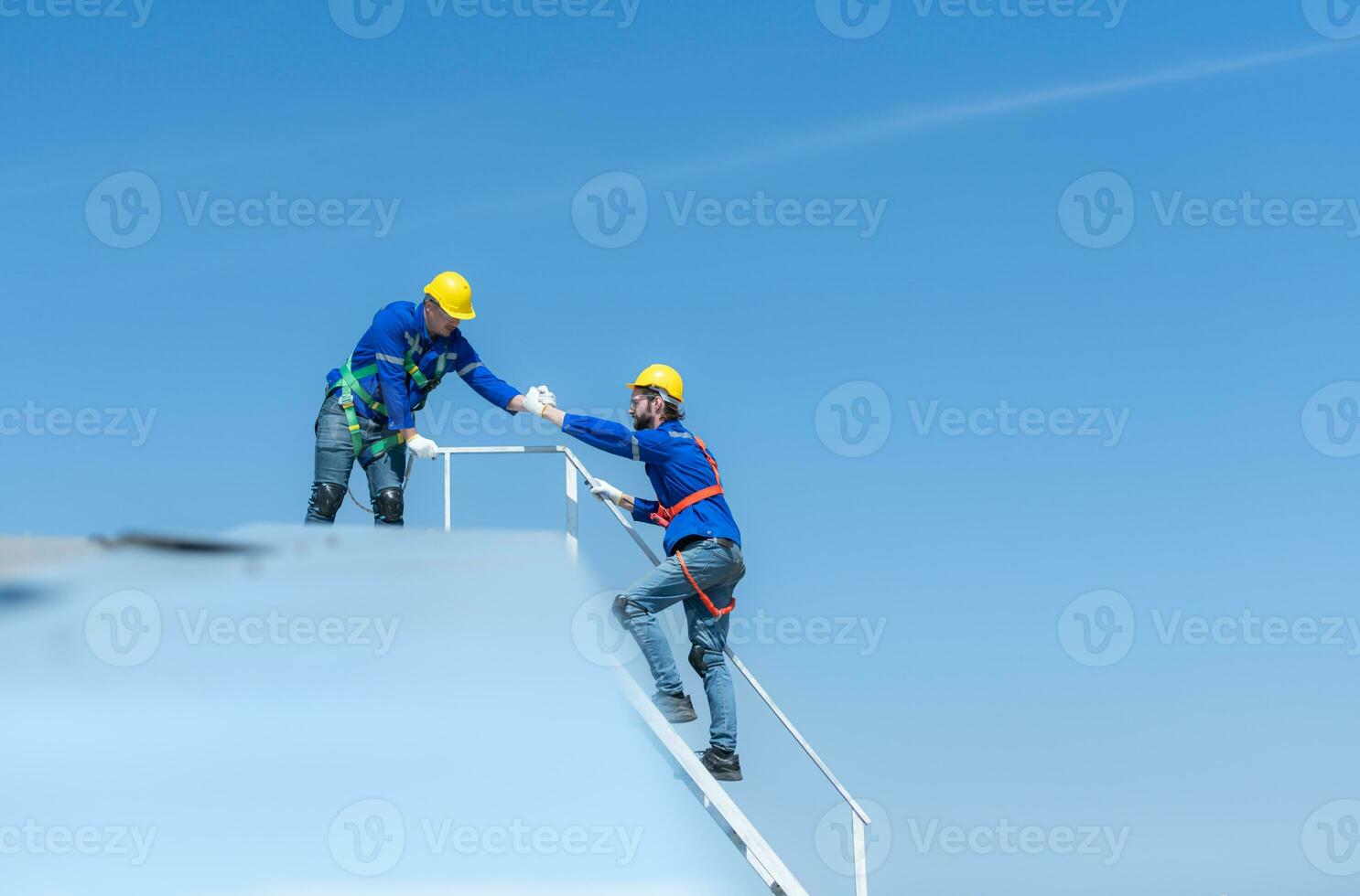 een jong technicus intern werken Aan zonne- panelen is angst van hoogten met senior ingenieurs wie zijn altijd helpen uit foto