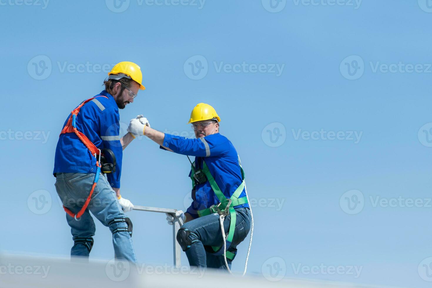 een jong technicus intern werken Aan zonne- panelen is angst van hoogten met senior ingenieurs wie zijn altijd helpen uit foto