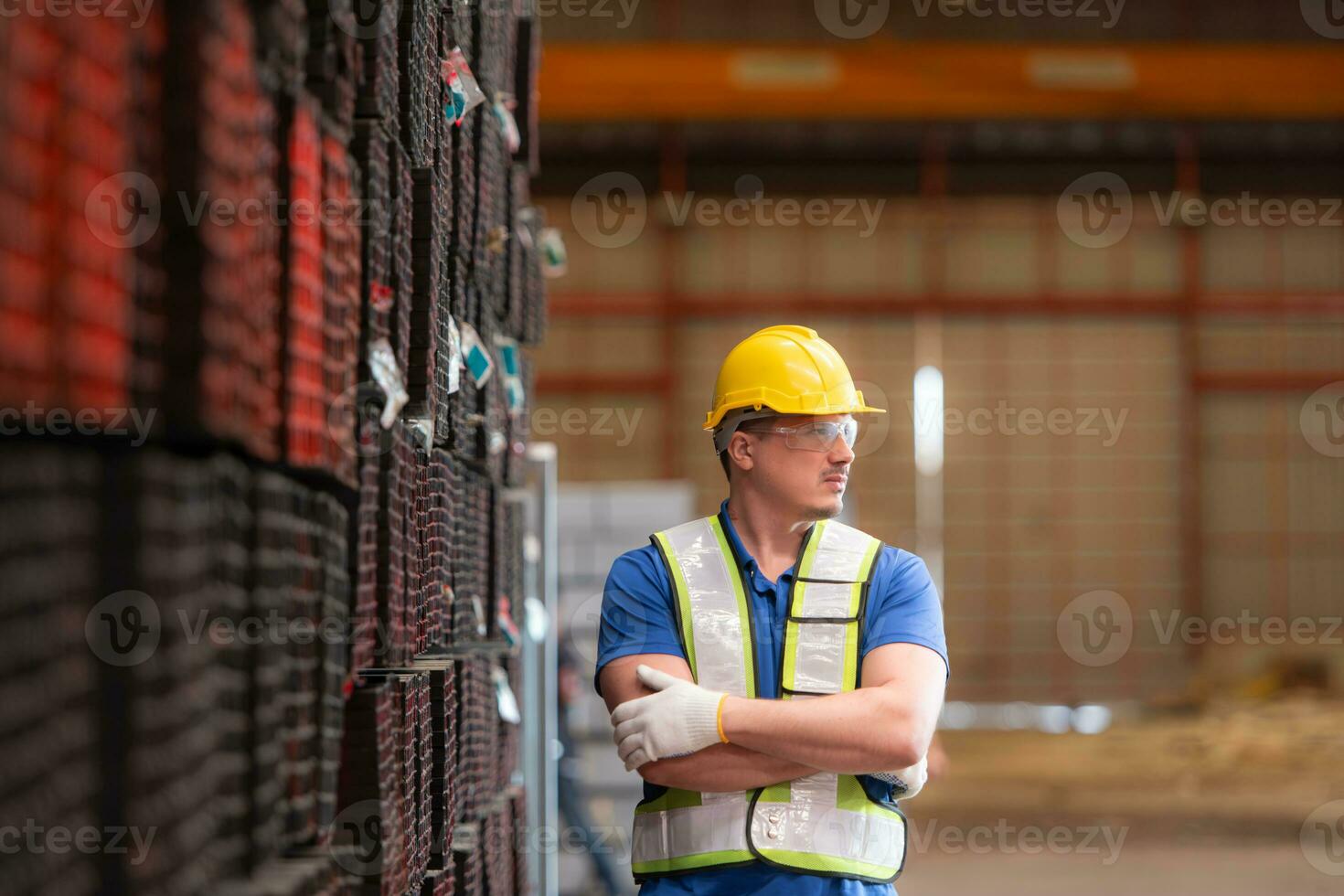 portret van een bouw arbeider staand met armen gekruiste in voorkant van staal materiaal muur foto