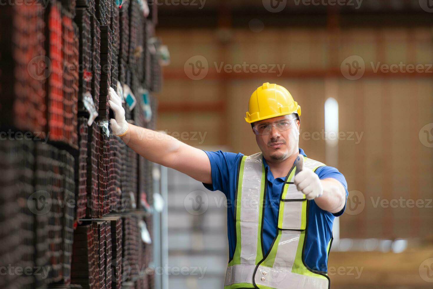 portret van een bouw arbeider staand met duimen omhoog in voorkant van staal materiaal muur foto