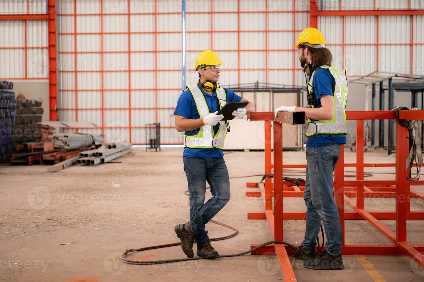 portret van twee arbeiders gebruik makend van digitaal tablet staan in voorkant van de rood staal structuur foto