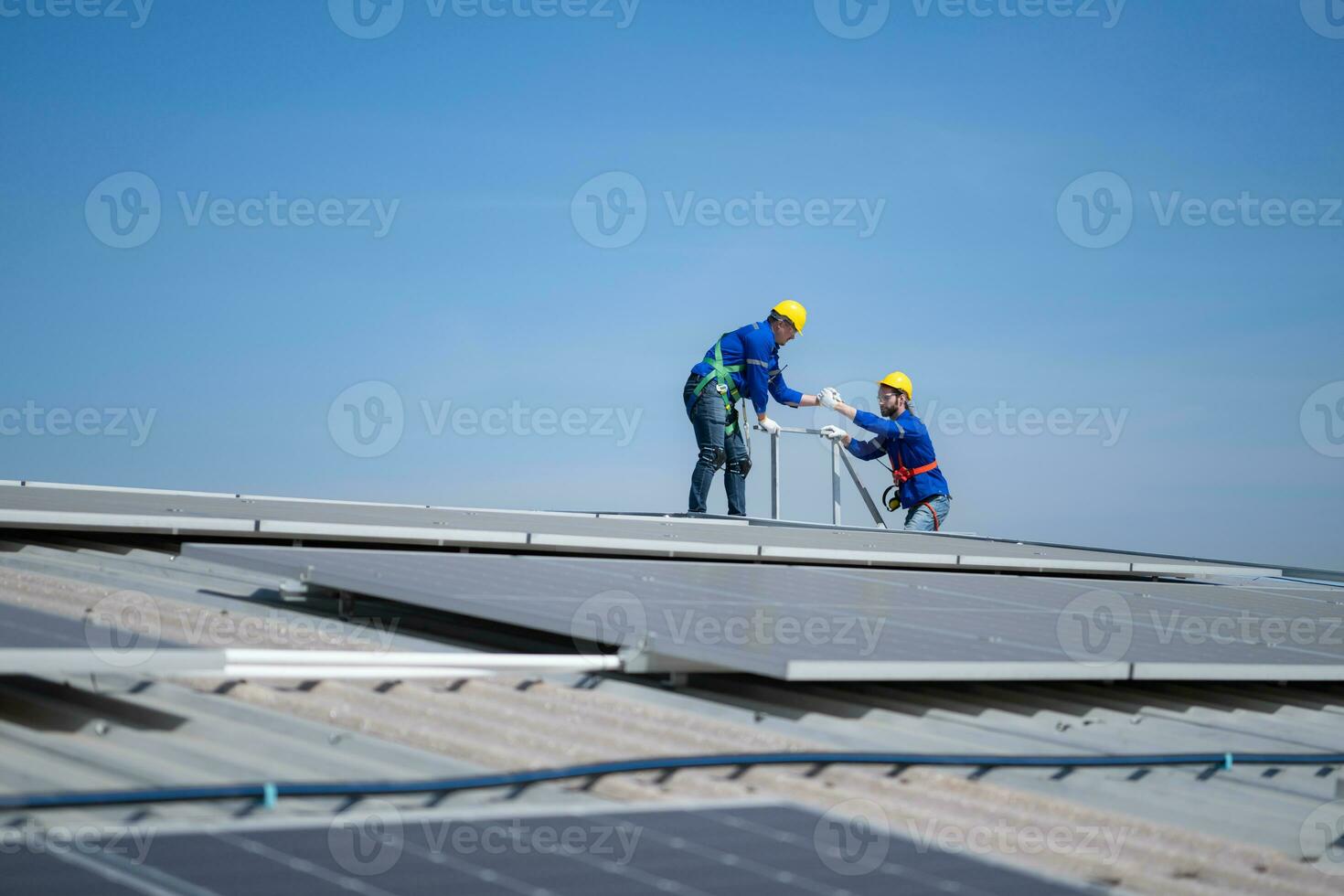 een jong technicus intern werken Aan zonne- panelen is angst van hoogten met senior ingenieurs wie zijn altijd helpen uit foto