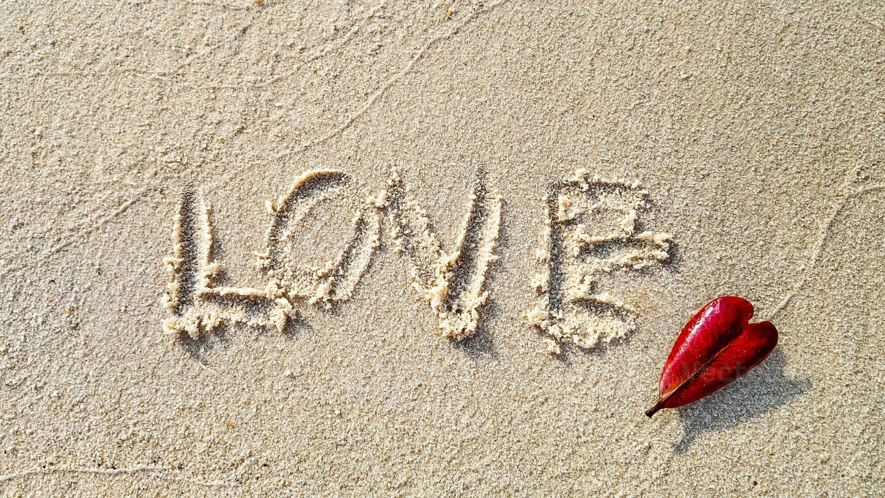 liefde ingeschreven Aan zand met hart blad foto