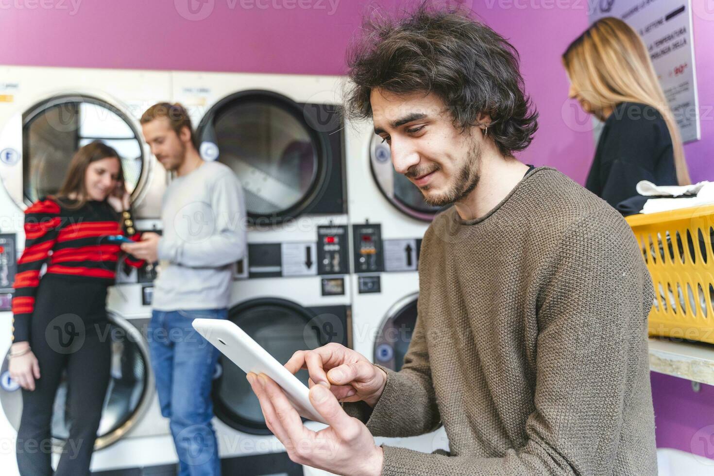 groep van verslaafd vrienden zijn spelen met tablets en smartphones in een openbaar wasserij foto