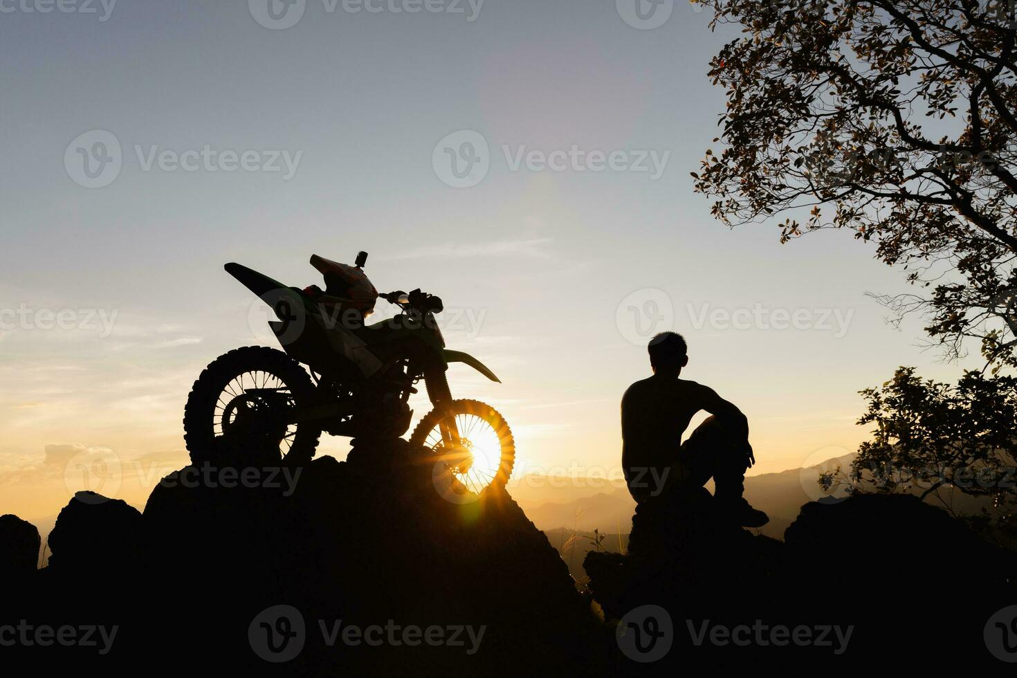 Mens met motorcross fiets tegen mooi lichten, silhouet van een Mens met motorcross motorfiets Aan top van rots hoog berg Bij mooi zonsondergang, enduro motorfiets reizen concept. foto
