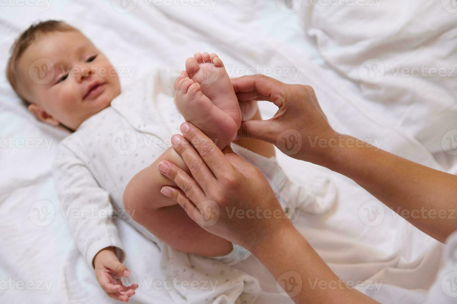 detailopname van weinig voeten met klein tenen van wazig aanbiddelijk baby jongen glimlachen op zoek Bij zijn mam knuffelen hem foto