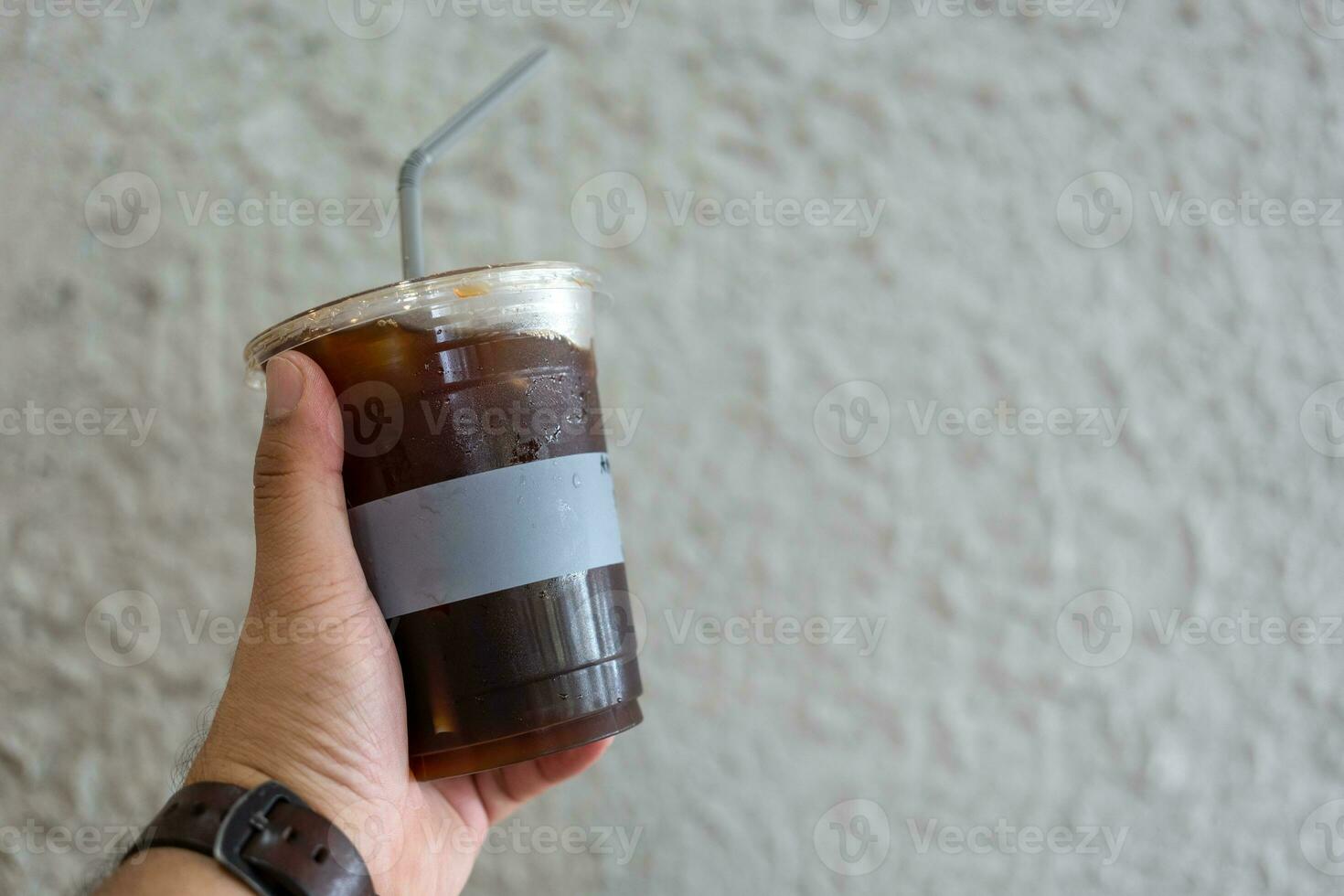 Mens Holding een transparant glas met koel zwart koffie foto