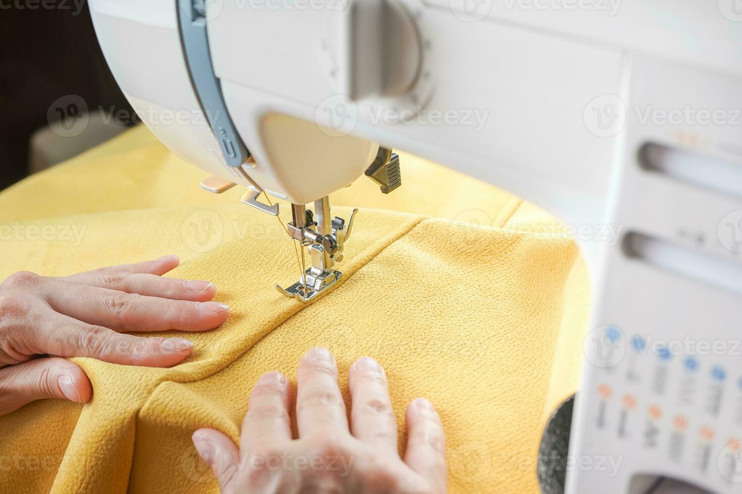 kleermaker handen stiksels geel kleding stof Aan modern naaien machine Bij werkplaats in atelier foto