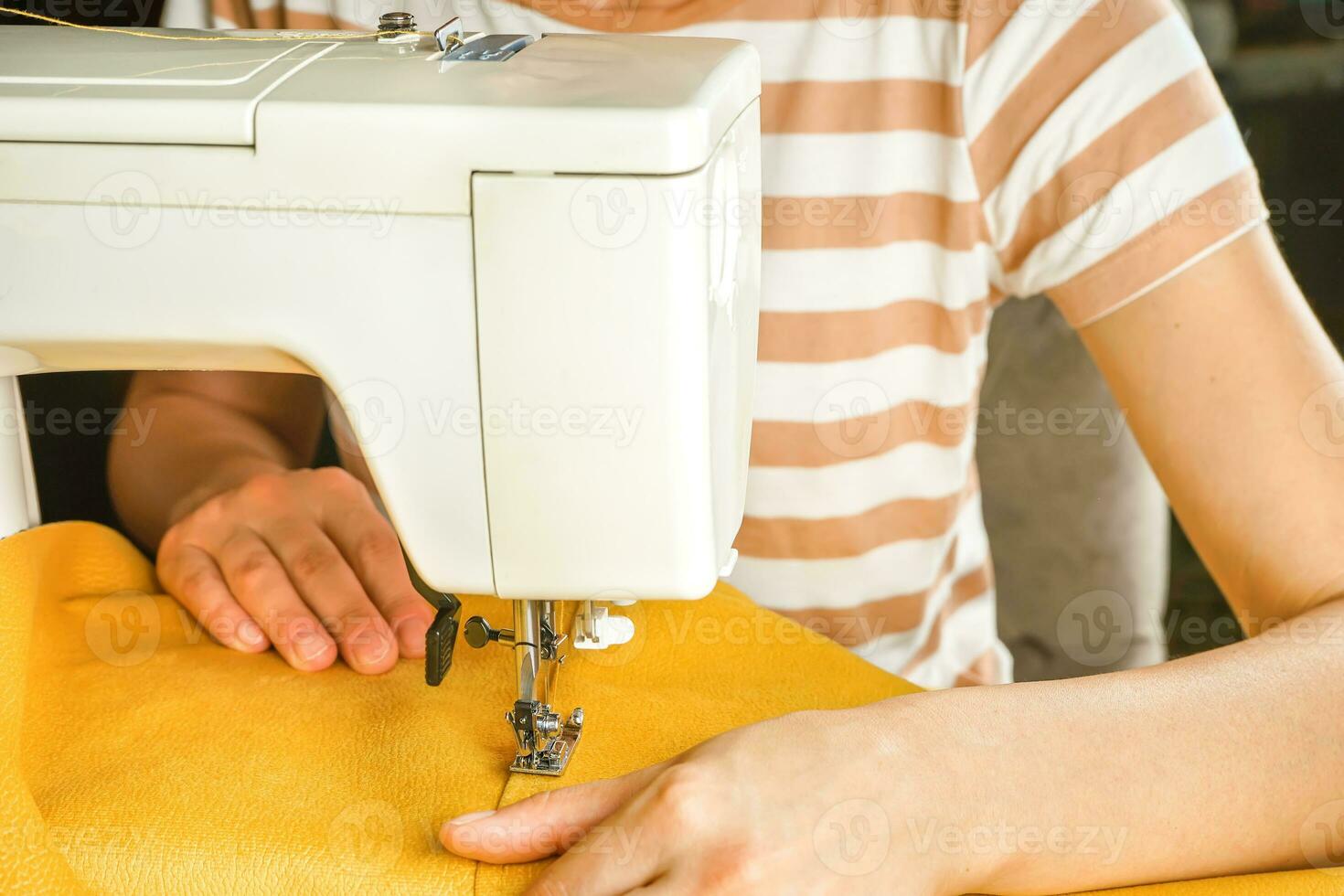 vrouw handen stiksels geel kleding stof Aan modern naaien machine. dichtbij omhoog visie van naaien werkwijze. foto