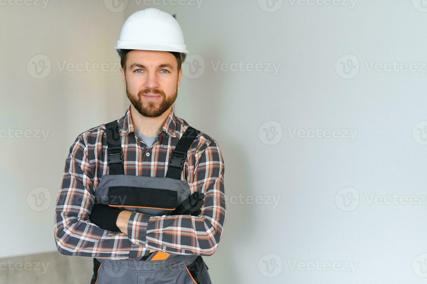 portret van positief, knap jong mannetje bouwer terwijl werken Bij bouw plaats. foto