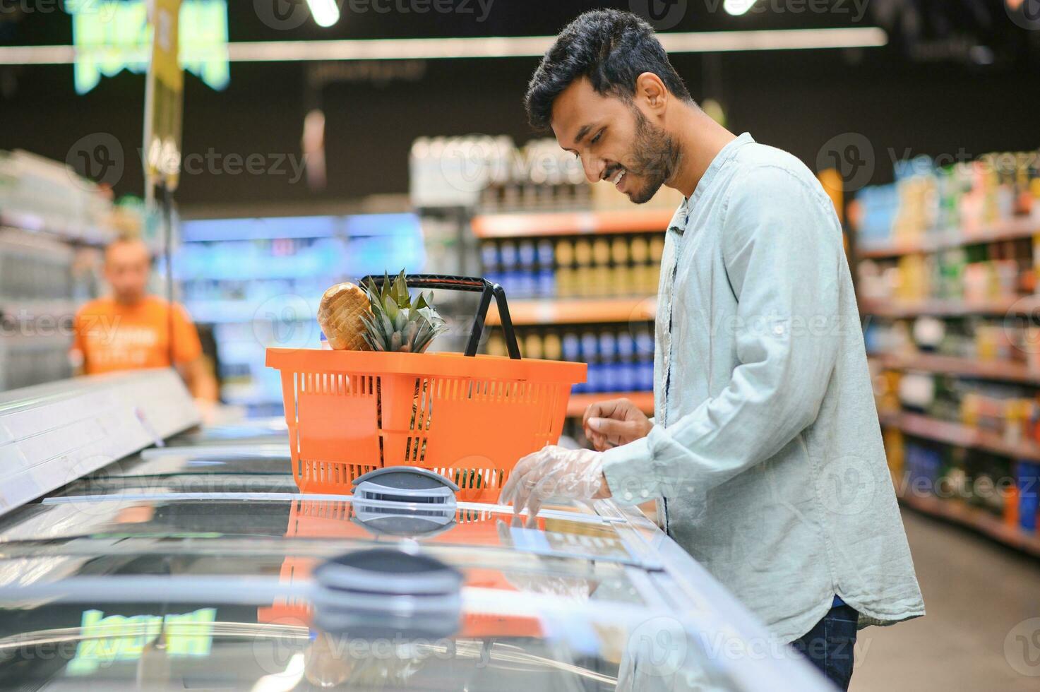 portret van gelukkig Indisch Mens staand in voorkant van de Product teller in een kruidenier op te slaan. Mens buying kruidenier voor huis in supermarkt. foto