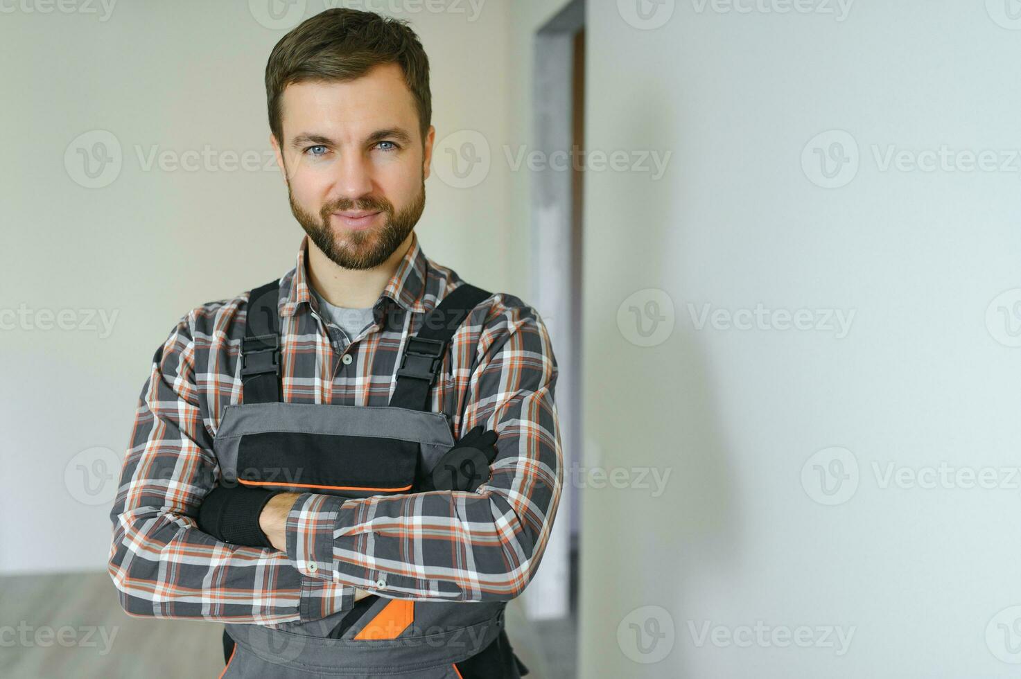 portret van positief, knap jong mannetje bouwer terwijl werken Bij bouw plaats. foto