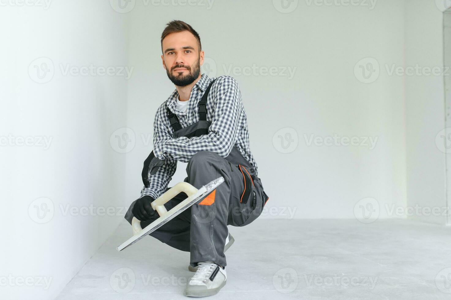 bedrijf, gebouw, beroep en mensen concept - bouwer met slijpen gereedschap binnenshuis foto