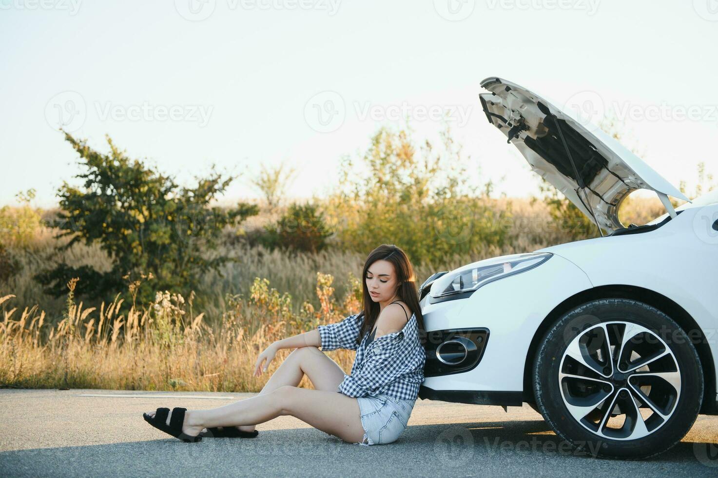 mooi jong meisje zittend Bij een gebroken auto Aan de weg ten einde raad naar krijgen helpen foto