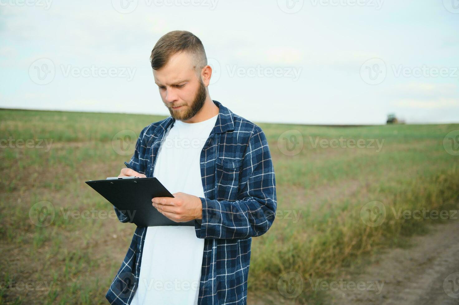 boer in een plaid overhemd gecontroleerd zijn veld- en schrijven notities. foto