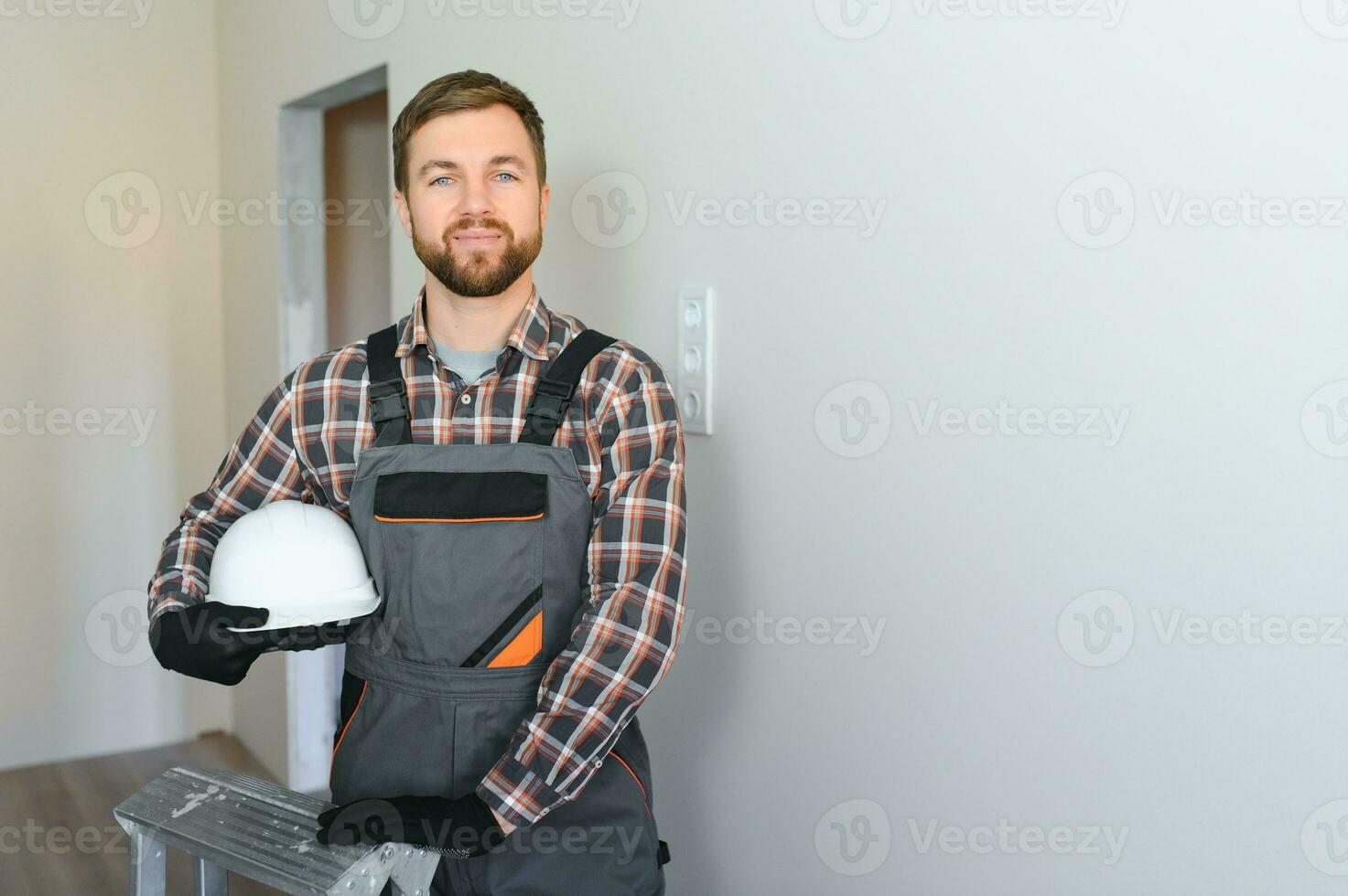 portret van een zelfverzekerd klusjesman met baard staand in leeg appartement foto