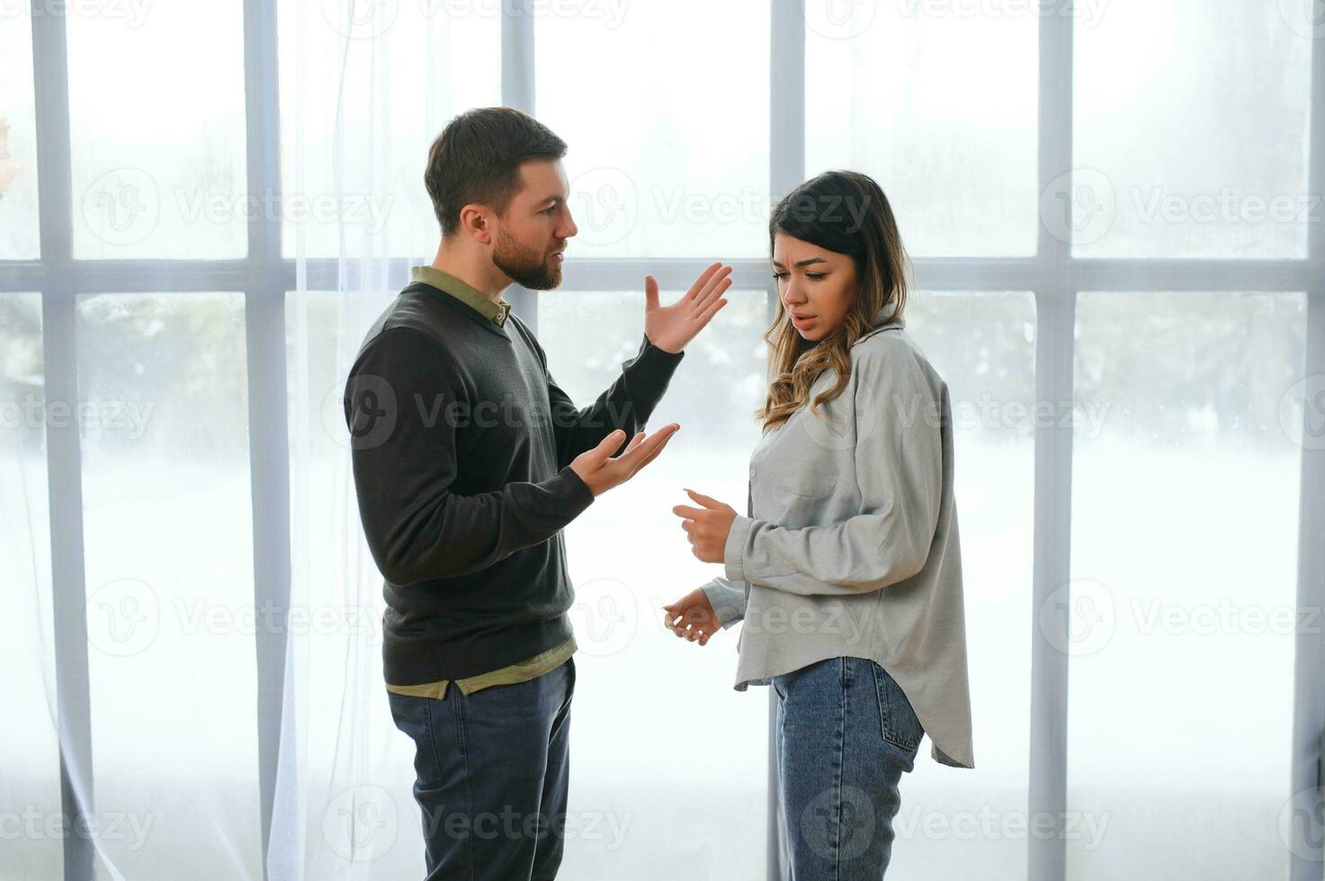 een opgewonden en van streek man schreeuwt en looks Bij zijn vrouw, een ruzie tussen echtgenoten. familie misverstand, ruzie foto