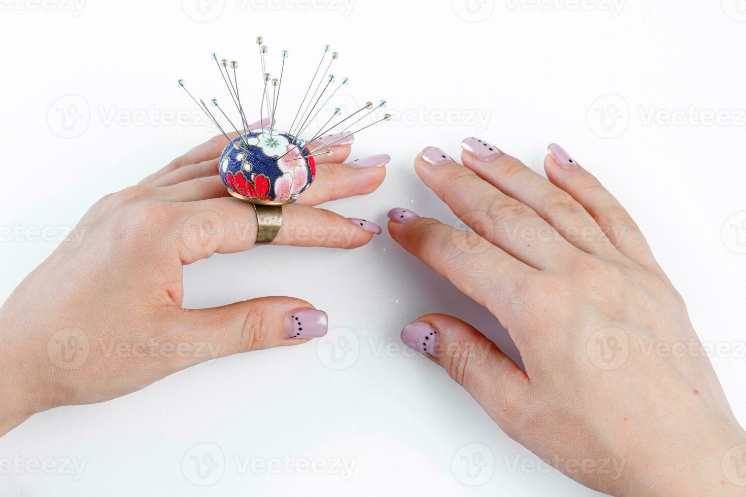 een ring met een klein hoofdkussen voor naalden Aan een hand- en schaar Aan een wit achtergrond foto