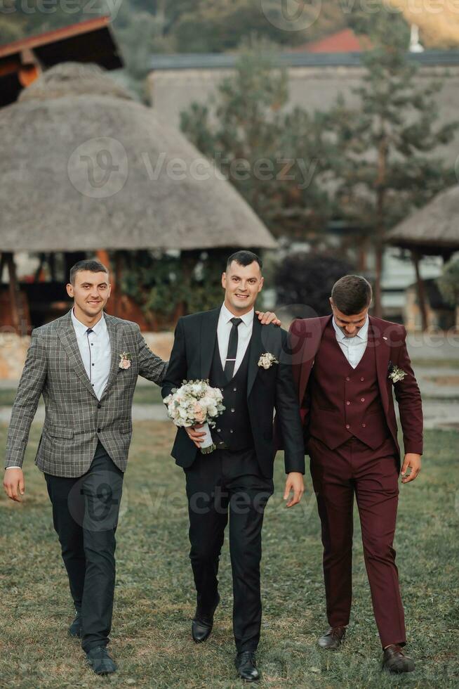 foto van drie mannen in klassiek pakken. een Mens houdt een boeket terwijl staand tussen zijn vrienden. bedrijf stijl. elegant mannen