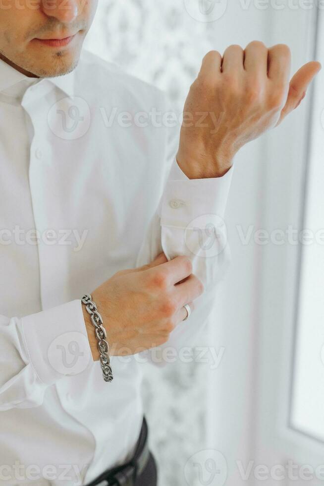 ochtend- van de bruidegom en details, wit shirt, mooi zo licht, jong Mens, elegant bruidegom krijgen gekleed, krijgen klaar voor de bruiloft ceremonie. detailopname van mannetje handen, foto