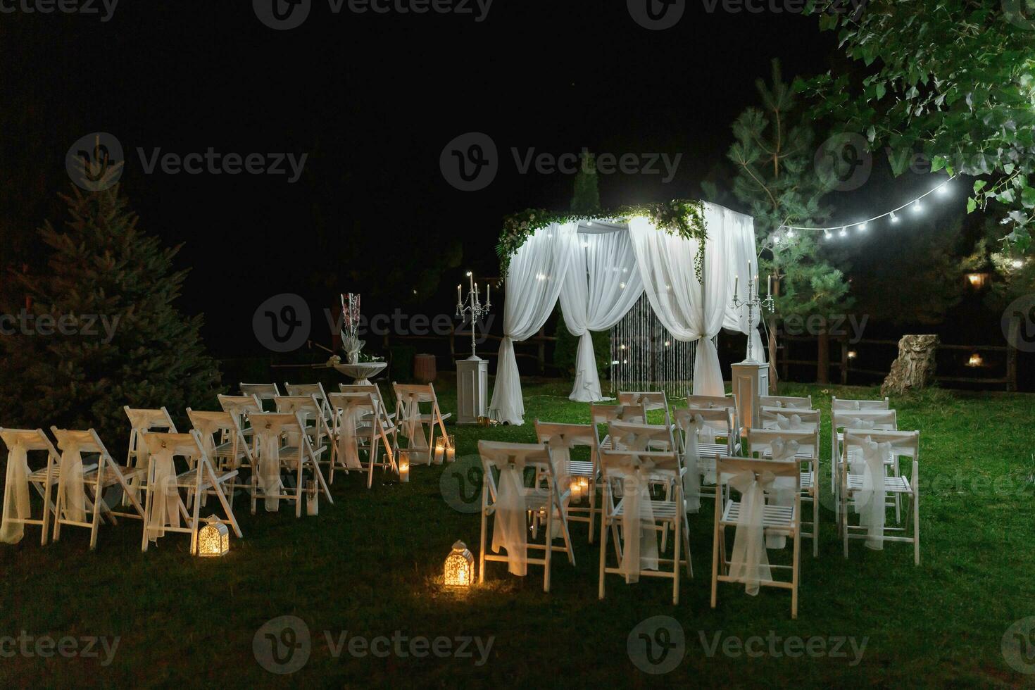 bruiloft ceremonie Aan de kust van de meer. schilderij ceremonie in de avond. romantisch schilderen. de presidium is versierd met wit bloemen. wit stoelen foto