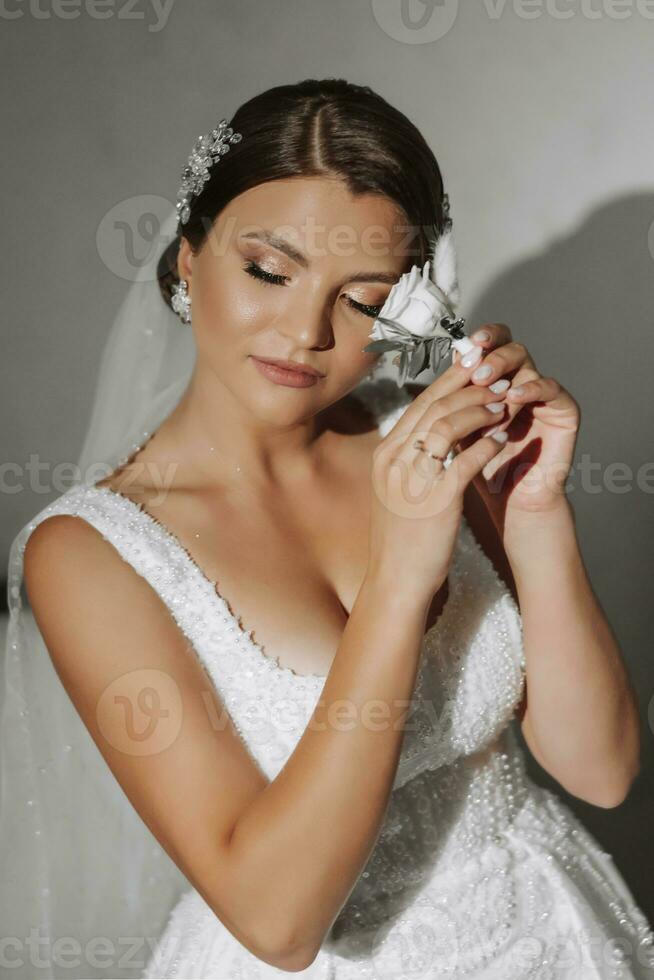 corsages voor de bruidegom in de handen van de bruid gemaakt van een wit roos vormig met decor. voorbereiding voor de vergadering van de bruid en bruidegom foto