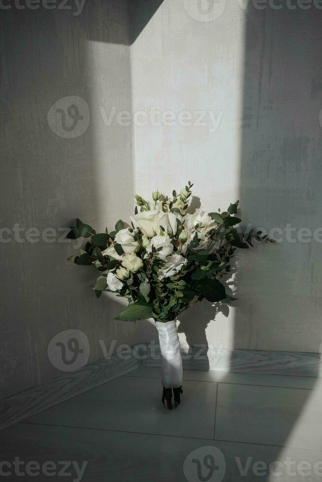 teder bruiloft boeket van wit rozen en groen, Aan een wit achtergrond, zon stralen en schaduw. bruiloft accessoires.. foto