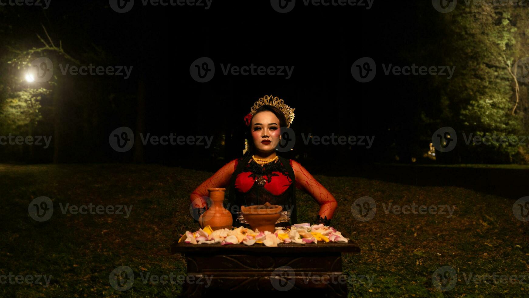 een vrouw danser presteert een ritueel dat creëert een magisch en mystiek atmosfeer in voorkant van bloem aanbiedingen foto